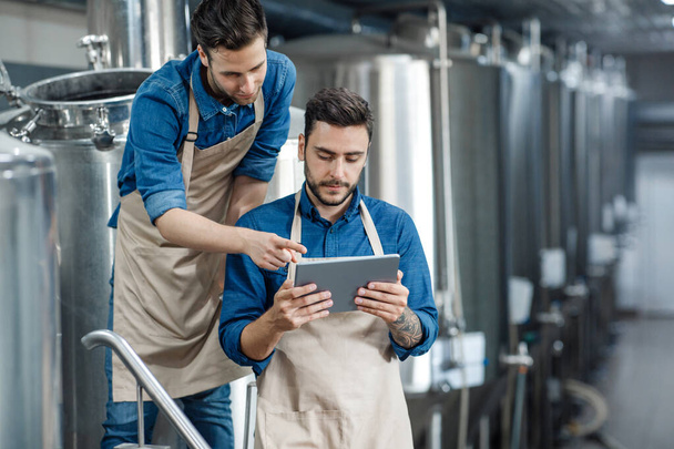 Muži inspektoři s digitálním tabletovým technikem kontrolují moderní pivní továrnu - Fotografie, Obrázek