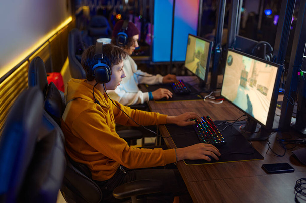 Two young gamers in headsets play in video game club - Foto, Bild