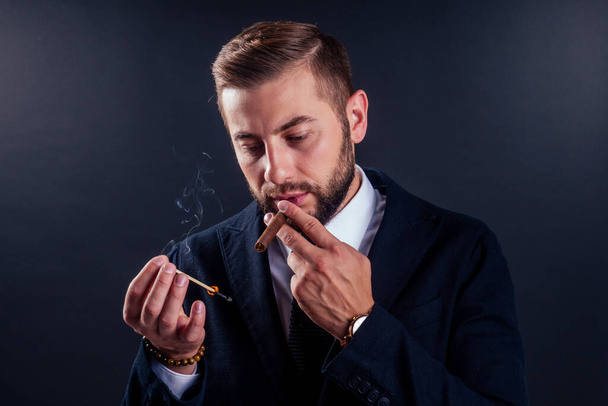 Portrait of an attractive business man with a cigar in black background studio - Fotografie, Obrázek