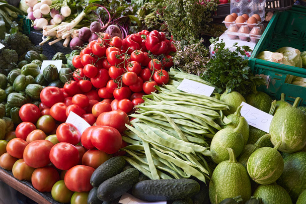 農家の市場に野菜と一緒に立ってください-トマト、キュウリ、エンドウ豆のポッド。ポルトガルのマデイラ州フンシャル. - 写真・画像