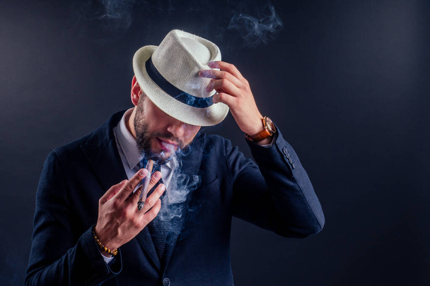 Portrait of an attractive business man with a cigar in black background studio - Fotó, kép
