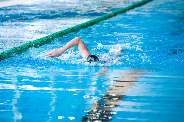 Yüzme yarışmasında yüzen kişi tek eliyle su üzerinde serbest stil vuruşu yapıyor. - Fotoğraf, Görsel
