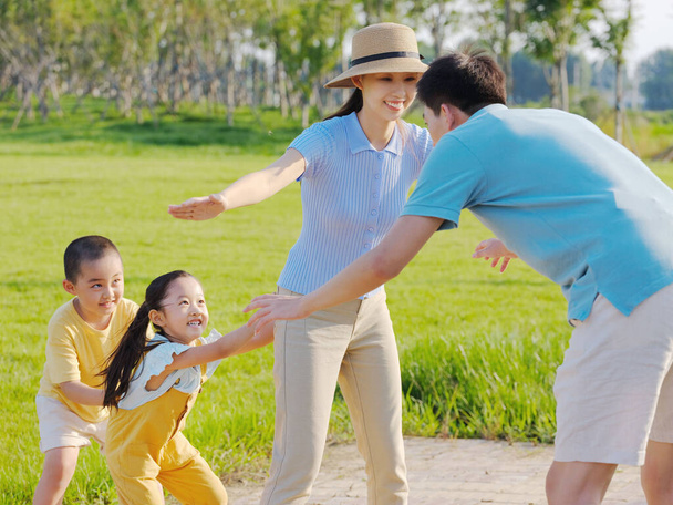 Happy family of four playing games in the park - 写真・画像