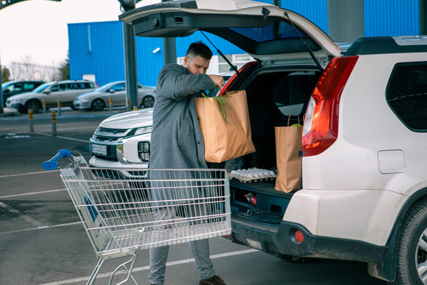 чоловік кладе сумки з продуктом у місце для копіювання багажника автомобіля
 - Фото, зображення