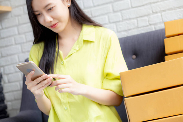 Jeune femme asiatique est entrepreneur vérifier l'ordre du smartphone avec le client lors de l'achat en ligne, logistique et livraison, achats en ligne, femme est vendeur de PME d'affaires, commerçant regardant téléphone. - Photo, image