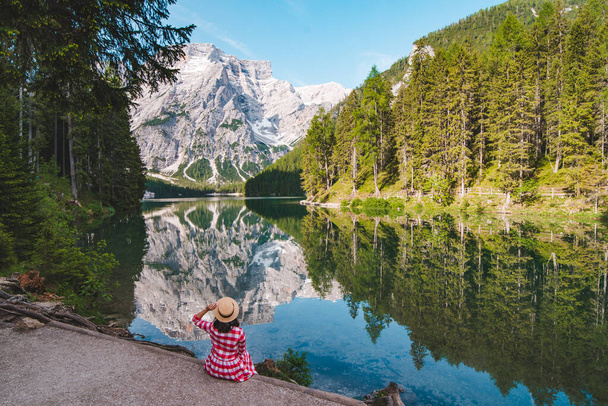 mulher em vestido xadrez vermelho com chapéu de palha olhando para o lago da montanha. férias de verão. conceito de viagem - Foto, Imagem