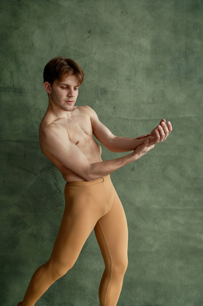 Mężczyzna baletnica, trening w klasie tańca, grunge ściany na tle. Wykonawca z umięśnionym ciałem, elegancja ruchów - Zdjęcie, obraz