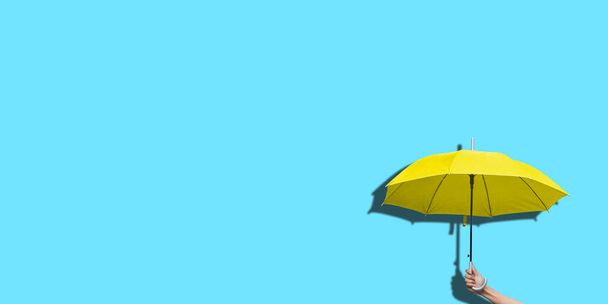 Şemsiyeyi renkli arkaplanda tutan adam tasarım için yer açtı. - Fotoğraf, Görsel