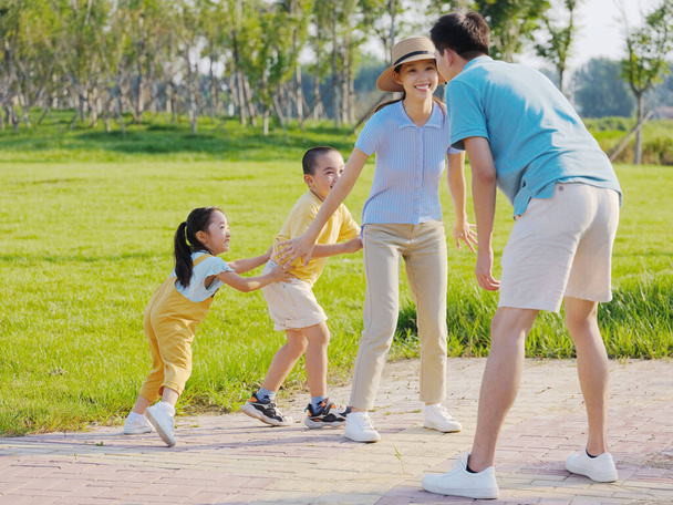 Happy family of four playing games in the park - Photo, Image