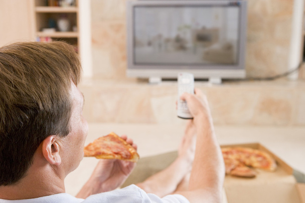 Homme appréciant la pizza tout en regardant la télévision
 - Photo, image