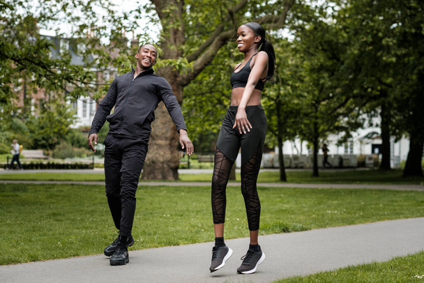 Fekete testvér és testvér ikrek testmozgást végeznek a szabadban elegáns sportruházatban. Egy parkban vannak és jól érzik magukat.. - Fotó, kép