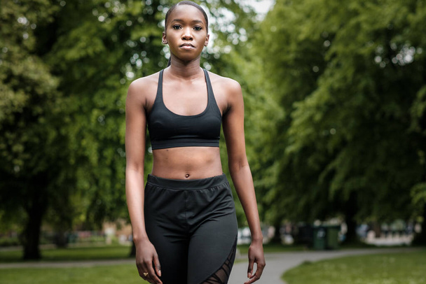 Schwarze junge Frau beim Sport in einem Park. Sie geht zuversichtlich in Richtung Kamera. - Foto, Bild