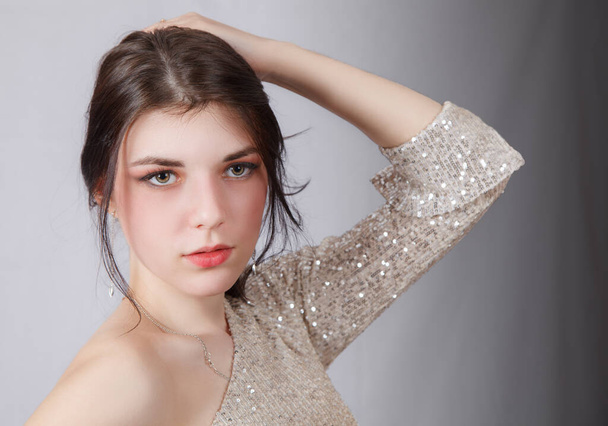 portrait of a young beautiful brunette girl in bright dress in studio on light background - Photo, Image