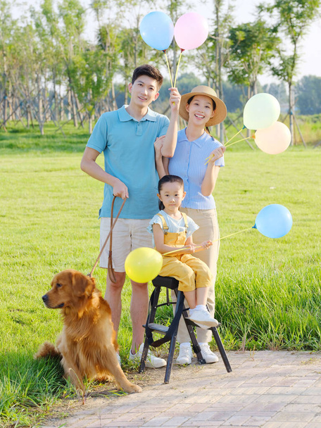 Happy family of three and pet dog in the park - Foto, Bild