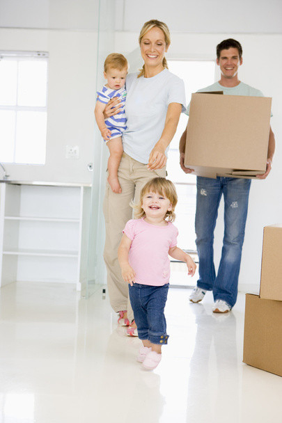 Family with box moving into new home smiling - Фото, изображение