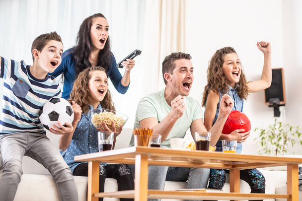 Raving fans cheering sports, as family of five watch football, match on the TV at home, screaming from joy. - Foto, afbeelding