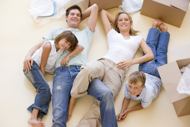 οικογένεια που βρίσκεται στο πάτωμα από τα ανοικτά κιβώτια στο νέο σπίτι χαμογελώντας - Φωτογραφία, εικόνα