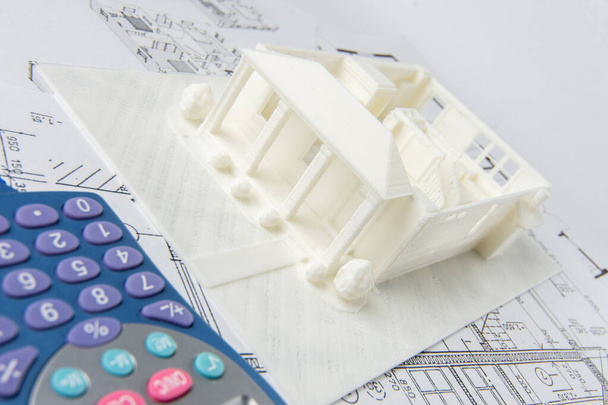 Close-up do modelo 3D da casa impresso em uma impressora 3D e calculadora. - Foto, Imagem