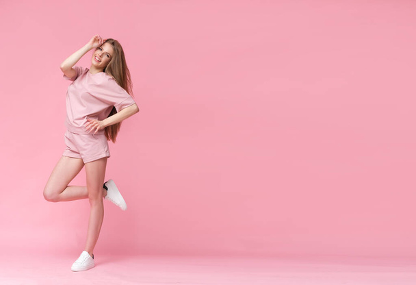 Süße Blondine mit langen Haaren auf rosa Hintergrund. - Foto, Bild
