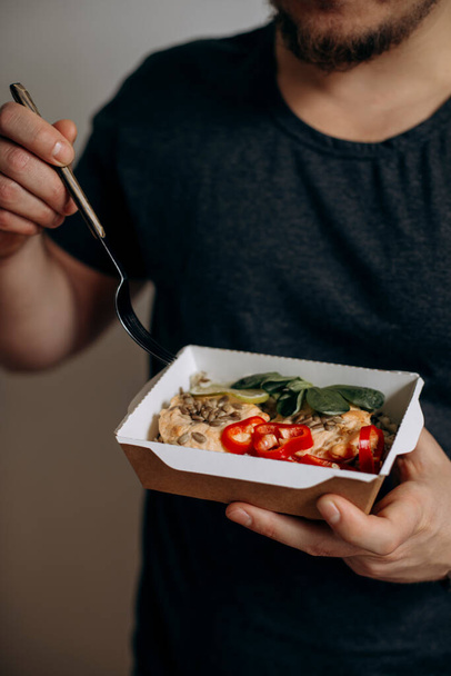 a man is going to eat healthy food in paper packaging. food in paper packaging in hands close-up. healthy food from delivery. concept of a healthy diet for modern young people. - Foto, Imagem