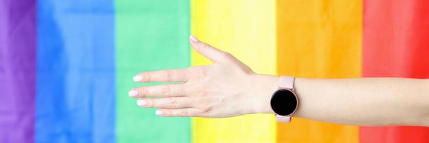Close-up van uitgestrekte hand met polshorloge tegen lgbt vlag achtergrond - Foto, afbeelding