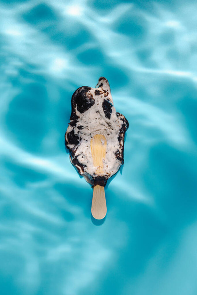 Melting ice cream stick in water. Sun and shadows. Minimal summer concept. Flat lay.  - Zdjęcie, obraz