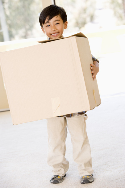 Young boy with box in new home smiling - Photo, image