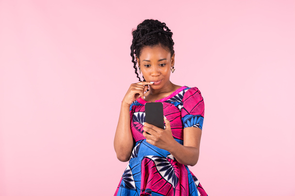Afro amerikkalainen nainen uteliaasti tarkistaa hänen puhelimensa: teknologian käsite. - Valokuva, kuva