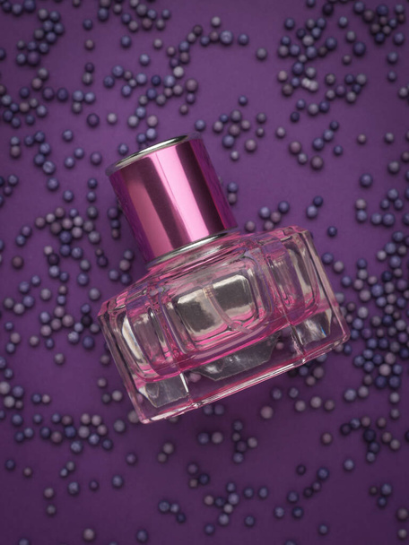 Frasco púrpura con perfume de mujer sobre fondo púrpura. Líquido aromático. - Foto, imagen