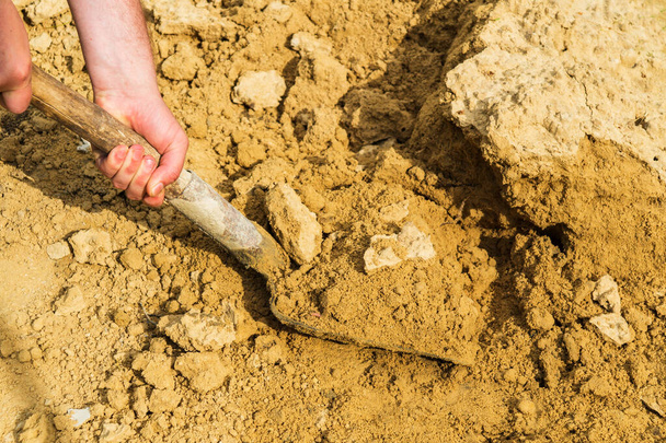 Gros plan de la main d'un constructeur ramasse du sable pour mortier avec une pelle. Fabrication de chape ou de plâtre de béton sur le chantier. - Photo, image