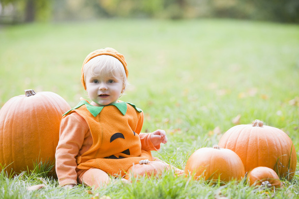Baby boy outdoors in pumpkin costume with real pumpkins - Foto, Imagem