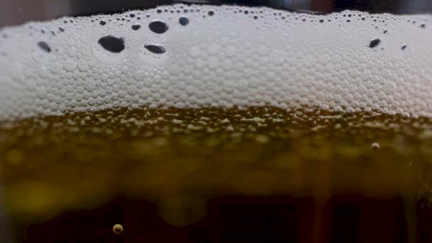 Κοντινό πλάνο της φούσκας μπύρας και αφρού που σχηματίζεται σε ένα διαφανές γυαλί, μακρο πυροβολισμό φυσαλίδων - Πλάνα, βίντεο