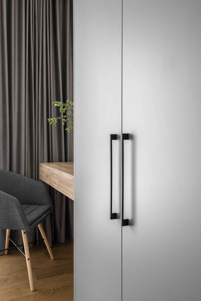 Eleganter Spiegel an Holzrahmenwand über minimalistischem Holztisch im trendigen Schlafzimmerinterieur in Grautönen - Foto, Bild