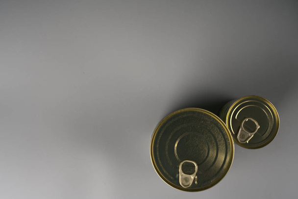 Two aluminum cans of golden color on a gray background. - 写真・画像