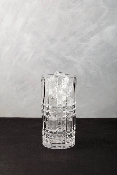 Ice cubes in tall cocktail glass. Grey background, copy space. Clear real ice for refreshing drinks. - Valokuva, kuva