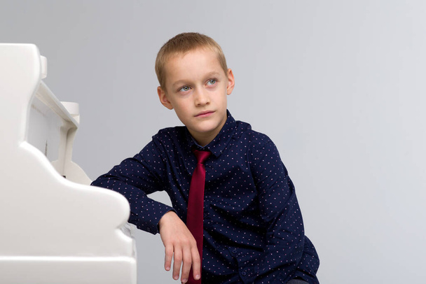 Preteen boy posing at grand piano - Valokuva, kuva