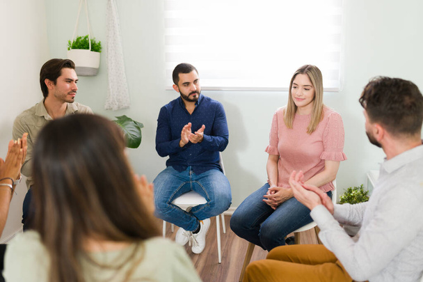 Beautiful woman sharing her progress with alcohol addiction at an alcoholic anonymous meeting. Support group clapping after a member shared her experience - Foto, Bild