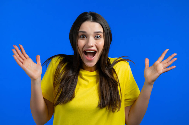 European woman is very glad, she screaming wow loud. Concept of sales, profitable offer. Excited happy lady on blue studio background. - Foto, Bild