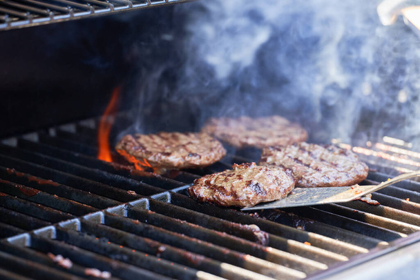 Cooking meat for burger on grill. Flame rising up from grid. - Foto, Imagem