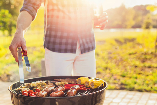 Delicious assorted grilled meat and sausages, with grilled vegetables with smoke and flame outdoors in the park in summer - Foto, afbeelding
