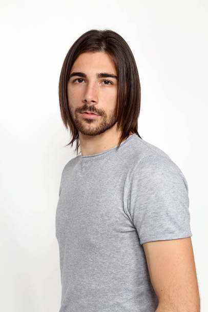 Attractive male model with long hair and beard posing in studio on isolated background. Style, trends, fashion concept. - Photo, Image
