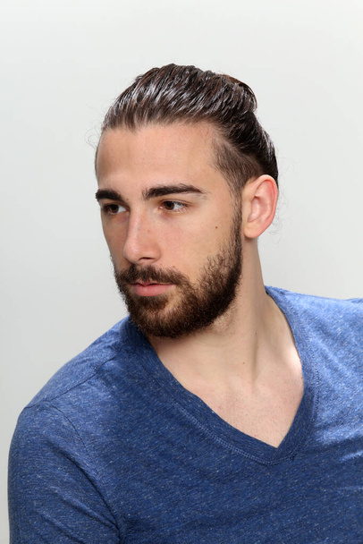 Attractive male model with long hair and beard posing in studio on isolated background. Style, trends, fashion concept. - 写真・画像