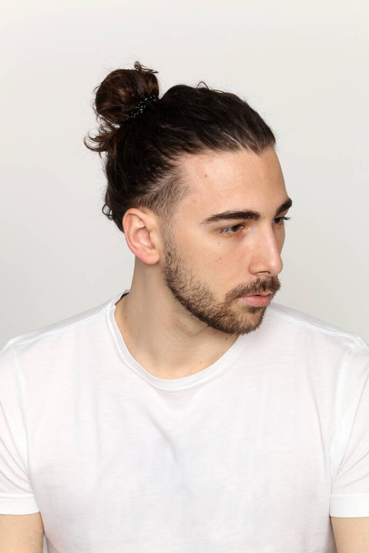 Atraktivní mužský model s dlouhými vlasy a vousy pózující ve studiu na izolovaném pozadí. Styl, trendy, módní koncept. - Fotografie, Obrázek
