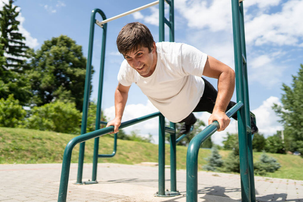Adult caucasian man training outdoor male doing push ups in sunny day street workout real people concept - Photo, Image