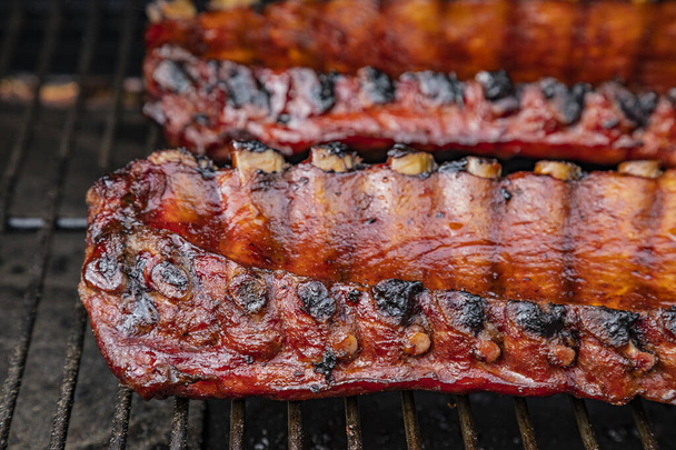 Close up of 2 racks of bbq ribs with barbeque sauce cooking on smoker grill, side view - Valokuva, kuva
