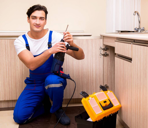Young repairman working at the kitchen - Photo, Image