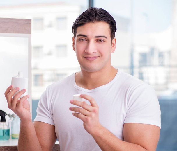 Young handsome man applying face cream - Фото, изображение