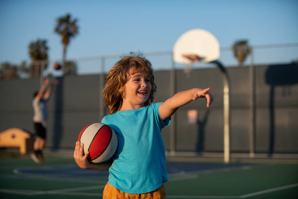 Basketballspiel. Kindertraining mit Basketball auf dem Basketballplatz im Freien. Kind zeigt Geste. - Foto, Bild