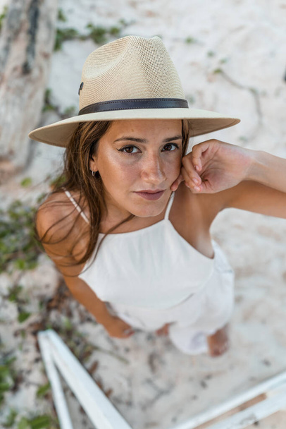young woman in hat looking up standing on sand in white clothes - Foto, Bild