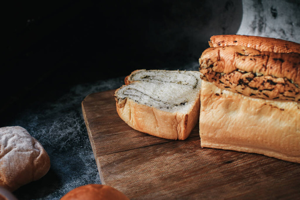 Φρέσκο σπιτικό ψωμί με τρούφα με ένα σεφ που κρατάει το χρυσό μαχαίρι για κόψιμο. Ψητά χρυσά ρουστίκ καρβέλια ψωμί και ψωμάκια. - Φωτογραφία, εικόνα